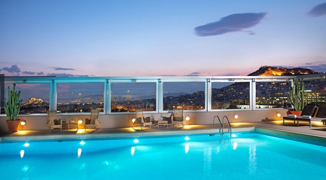 a pool with chairs and a view of a city