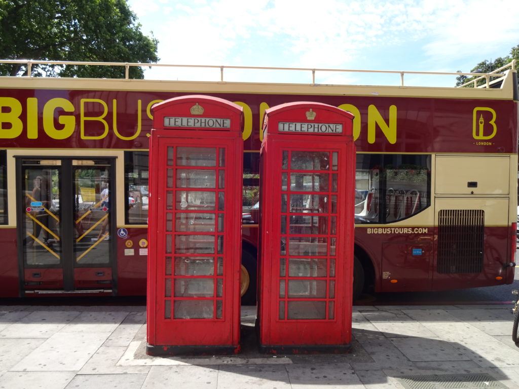 a red telephone booth next to a bus
