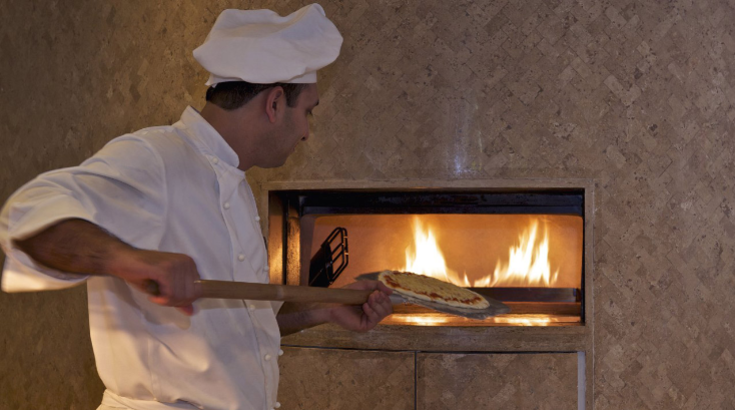 a chef putting pizza on a pizza pan