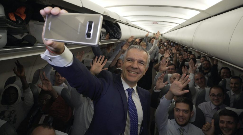 a man in a suit taking a selfie with a group of people