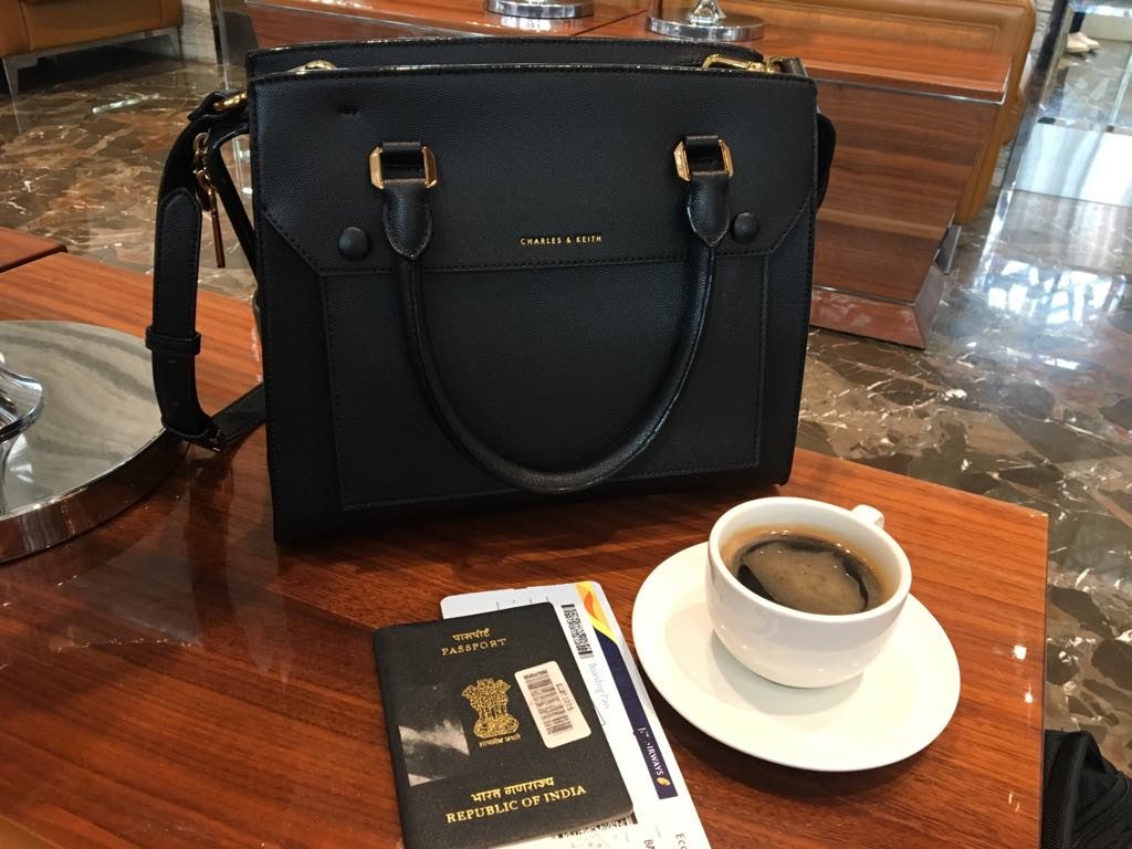 a black purse and a cup of coffee on a table