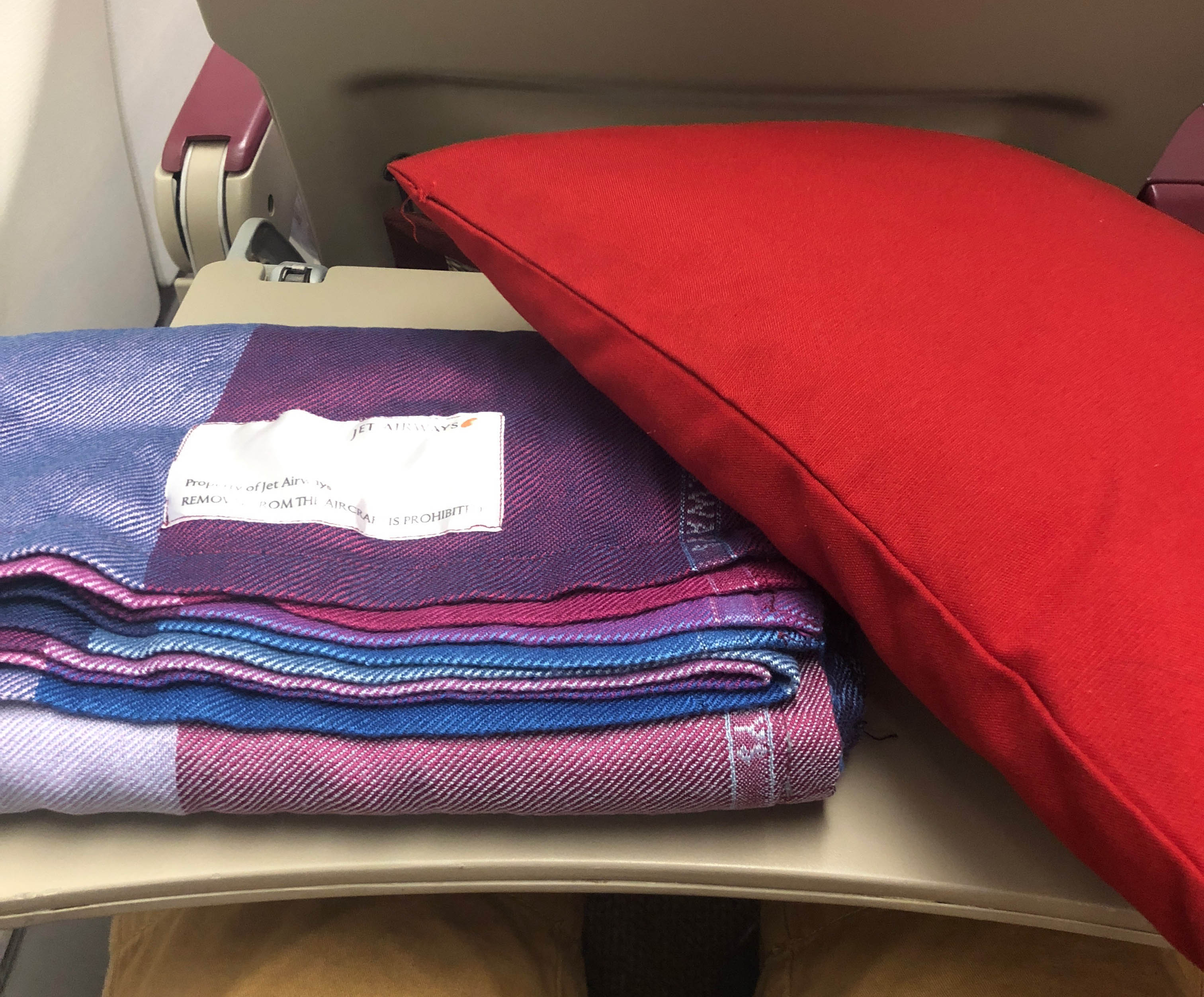 a red pillow and a stack of blankets on a plane