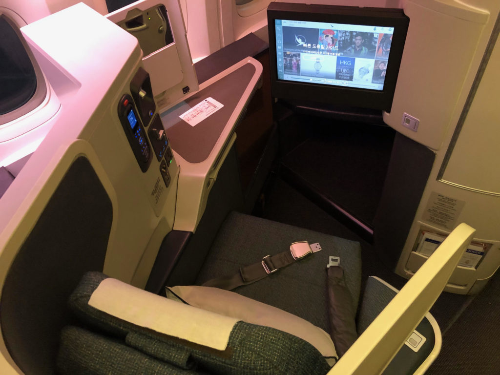 a seat with a seat belt and a monitor in the back of a plane