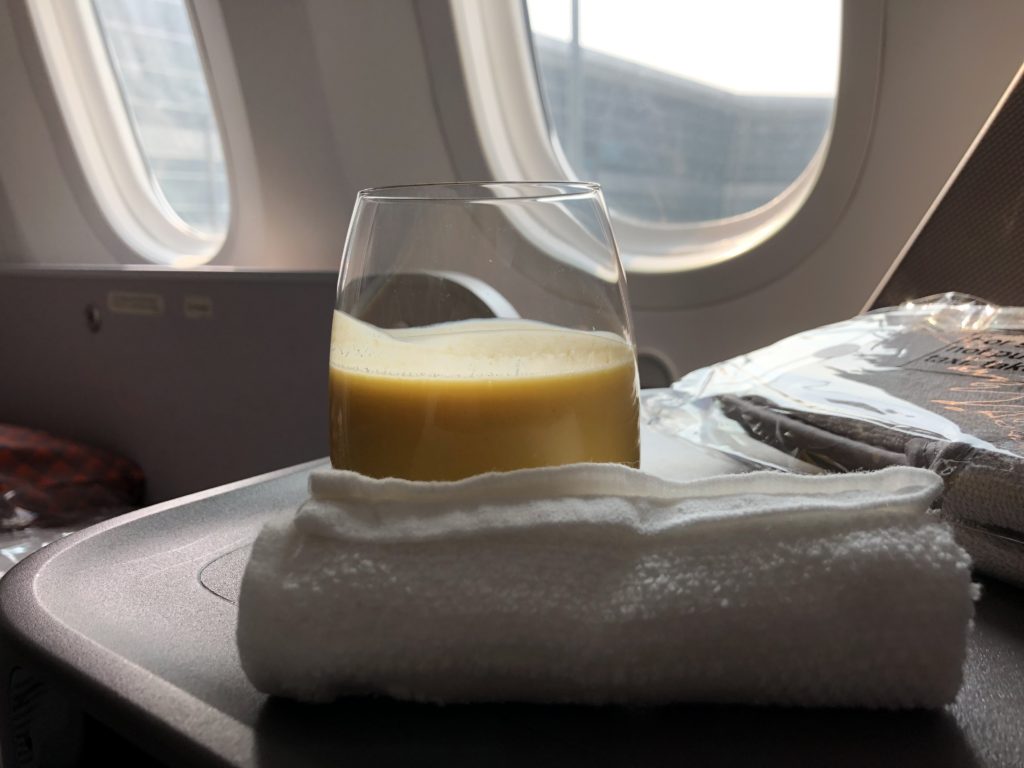 a glass of yellow liquid on a towel on a table