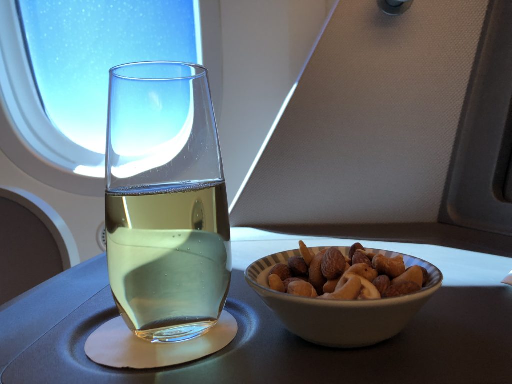 a glass of liquid and a bowl of nuts on a table