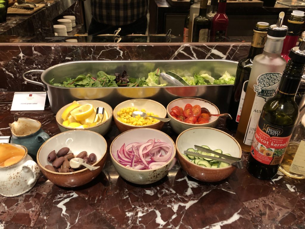 a salad bar with bowls of food and bottles of wine