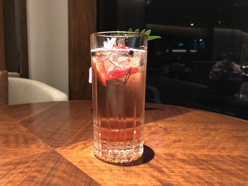 a glass of liquid with ice and strawberries on a table
