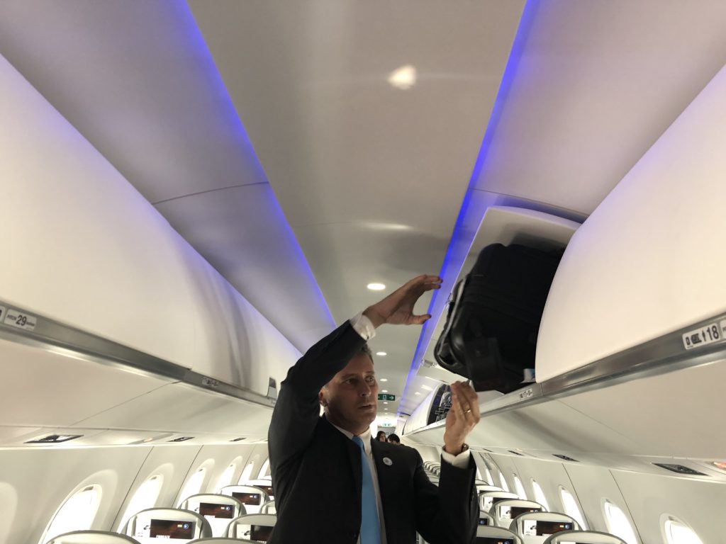 a man in a suit holding a suitcase in an airplane