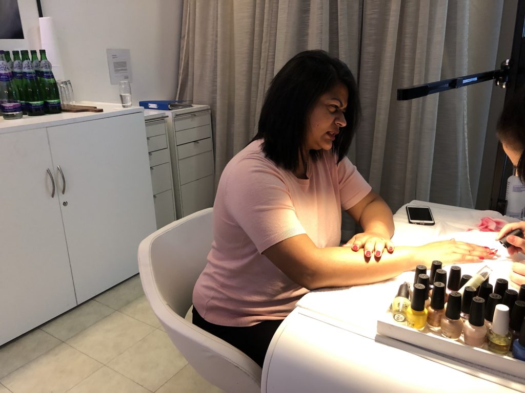 a woman sitting at a desk with nail polish