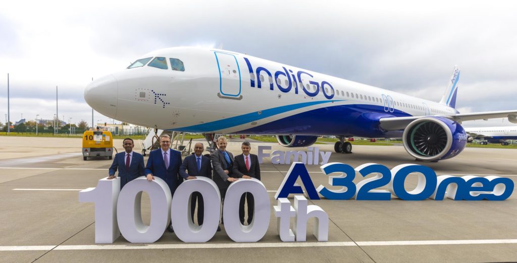 a group of men standing in front of a large white and blue airplane