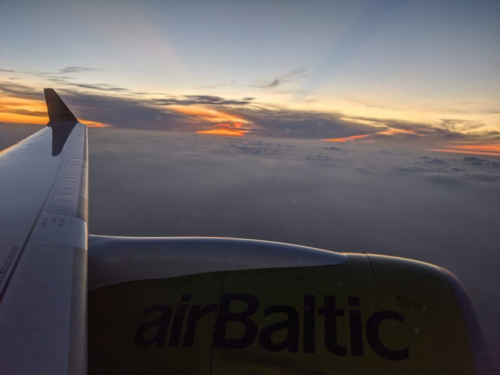an airplane wing with clouds and a sunset