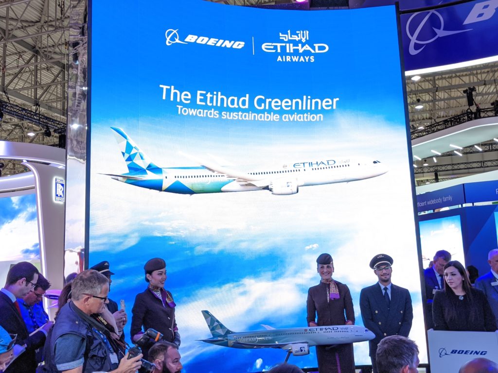 a group of people standing in front of a large sign with an airplane