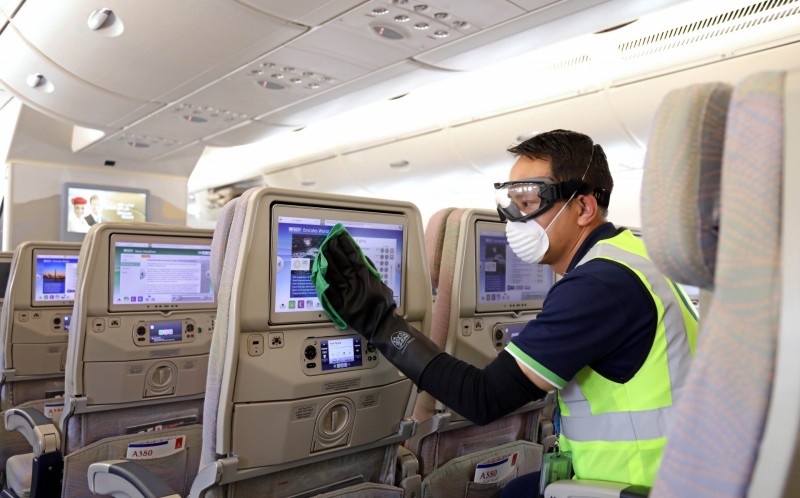 a man wearing a safety vest and gloves cleaning an airplane