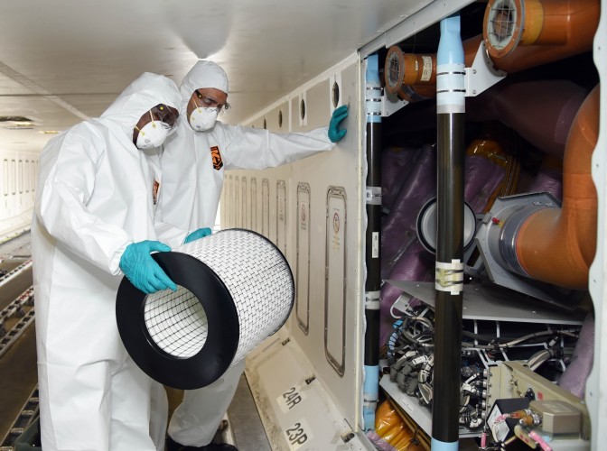 a man in white hazmat suit and mask holding a large round white cylinder